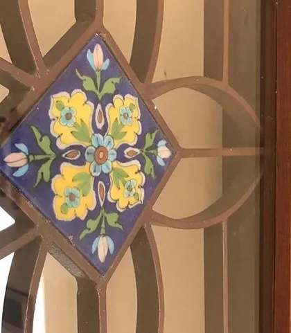 A close-up view of the hand-painted ceramic tile inlaid into the custom window grille at the Roopa Hariprasad Residence. This level of detail exemplifies our focus on integrating artisanal craft into our architectural projects.