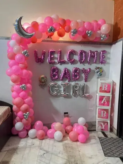 A detailed look at the pink balloon arch, featuring a mix of bright pink, light pink, and white balloons with silver accents and 'BABY' blocks.
