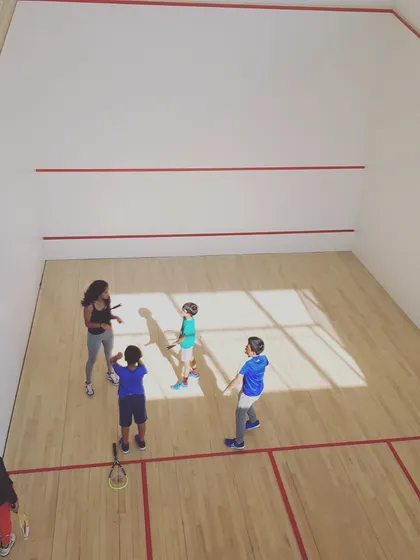 A high-angle view of one of our coaches working with our youngest group of players. We make learning the basics of squash engaging and accessible for all age groups.