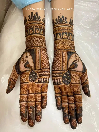 A bold and elegant engagement mehandi featuring symmetrical peacock motifs. The design combines traditional Indian patterns with negative space to create a striking look.