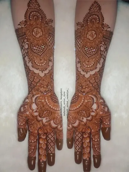 A classic bridal design with a central floral motif surrounded by delicate patterns, extending up the arm.