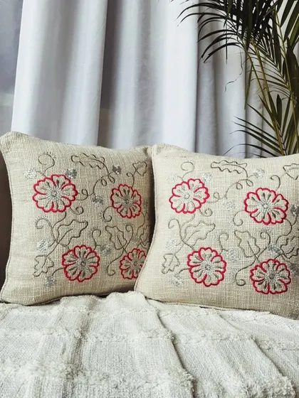 This slub cotton cushion cover features a delicate red and silver floral embroidery, adding a touch of traditional elegance to your home.