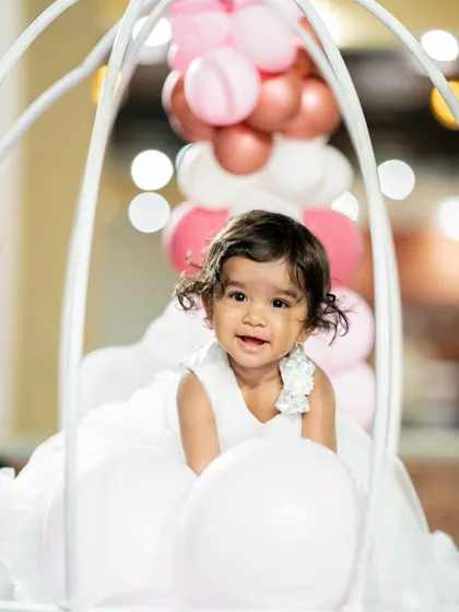 The birthday girl looking adorable in a hot air balloon prop. We design unique photo opportunities to capture the magic of the day.