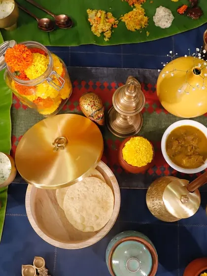 A beautifully arranged Sadya table, showcasing the vibrant colors of the Vishu festival. The spread includes seasonal dishes made with jackfruit, mango, and pumpkin, all served in traditional brassware that adds to the festive feel.