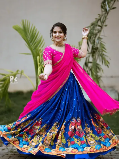 A regal half saree featuring a royal blue lehenga with a traditional printed border, paired with a bright pink embroidered blouse.