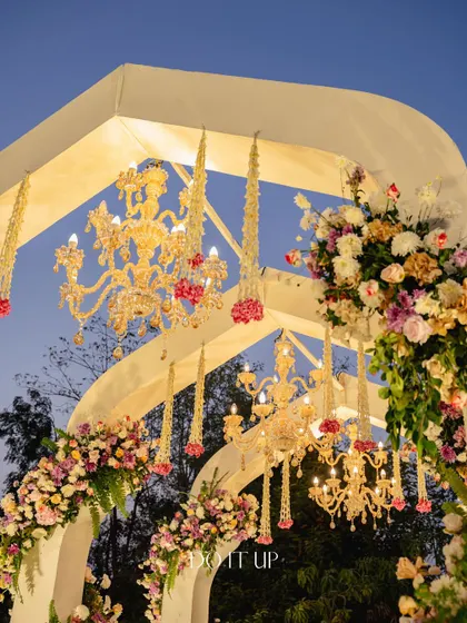 The mandap from the Jaipur wedding, illuminated at dusk. The structure, adorned with pastel florals and multiple chandeliers, created a breathtaking sight against the evening sky.