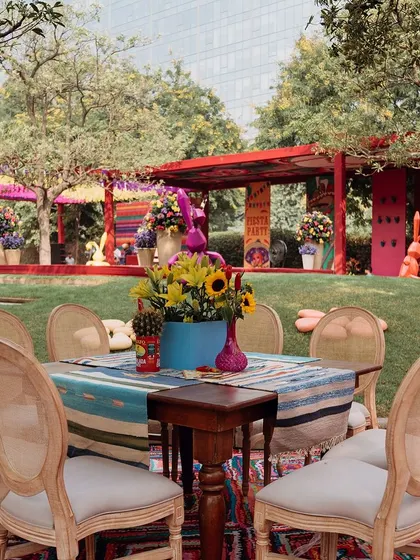 A dining table set in the garden, with the lush greenery providing a beautiful natural backdrop to the colorful decor.