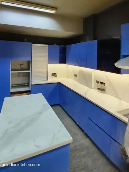 Another angle of the blue kitchen installation, showing the island with a white marble-effect quartz top. The layout is designed for both functionality and a strong visual impact.