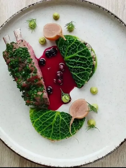 A rack of lamb with a herb crust, served with a rich berry sauce and cabbage leaves. A sophisticated main course for a formal dinner.