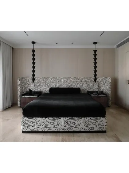 The master bedroom features a bold, graphic-print fabric on the headboard and bed base. This is contrasted with minimalist, cone-shaped pendant lights, creating a space that is both artistic and modern.