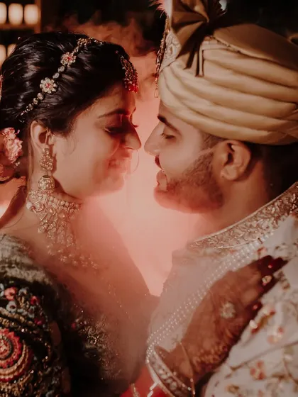 A dramatic and intimate close-up of a bride and groom on their wedding day, enveloped in warm light and smoke, capturing the intensity and emotion of the moment.