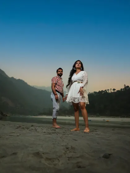 A powerful, fashion-inspired pre-wedding shot on the sandy banks of the river in Rishikesh. Their confident poses against the blue sky create a striking and modern portrait.