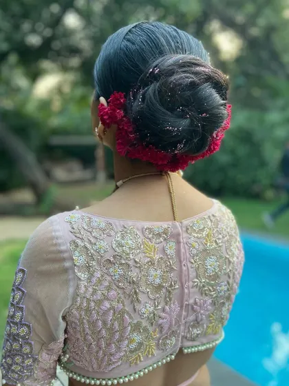 A full view of the high bun with red coxcomb flowers, a perfect hairstyle for a bride who wants a touch of drama and tradition.