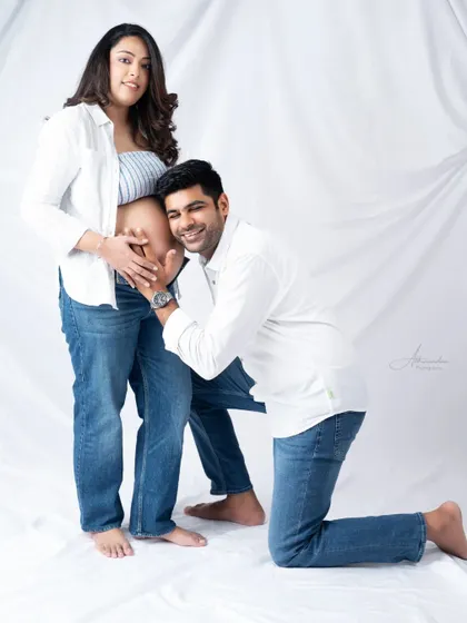 A happy and classic pose. The dad-to-be listens to the baby bump, and his bright smile says it all.