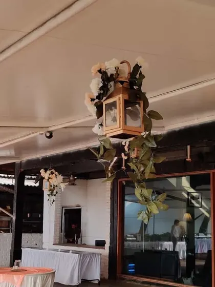 A hanging wooden lantern decorated with flowers and greenery. These were used as part of the ceiling decor to add a rustic and romantic touch to the venue.