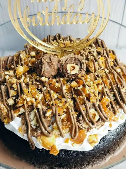 A close-up of the Choco Rocher Tres Leches, highlighting the irresistible textures of crunchy hazelnut praline, creamy frosting, and a whole Ferrero Rocher.