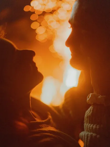 A silhouette of the couple against the warm, bokeh lights of a bonfire. This artistic shot focuses on their profiles and the intimate space between them.