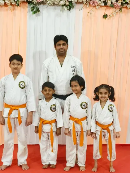 A group of proud orange belt recipients at the Rejoice International School distribution event, excited for their next challenge.