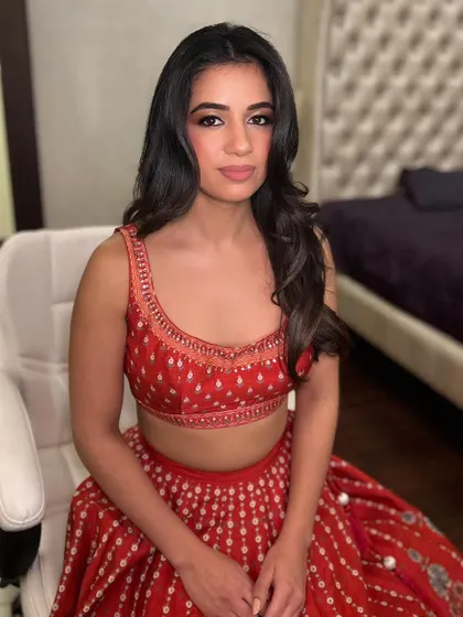 A client ready for a festive event in a vibrant red lehenga. We styled her with soft, open curls and a natural makeup look that enhances her features without overpowering the outfit.