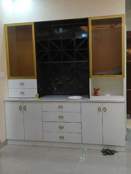 We design custom crockery and bar units to fit your living space. This unit features an inbuilt wine rack, fluted glass shutters, and a mix of drawers and cabinets for organized storage.