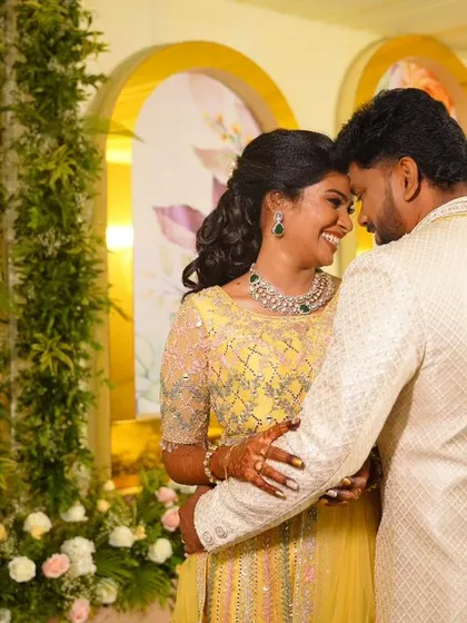 A romantic portrait of my bride Abhinaya and her groom. Her reception look features a bright yellow lehenga, soft curls, and makeup that makes her glow with joy.