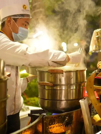 A chef at our live station, tending to large multi-tiered steamers filled with delicious, hot momos, ready to be served.