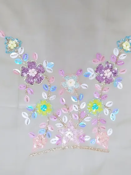 This image shows a neckline motif created with multi-colored sequins and beads. This kind of detailed hand-embroidery allows me to create completely custom patterns that reflect your personal style and the theme of your event.