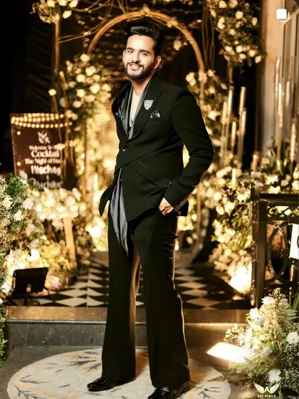 YouTuber Fukra Insaan styled in our unique black cocktail suit for his brother's wedding. The outfit features an asymmetric wrap-style blazer with a draped satin element, creating a modern and edgy silhouette.