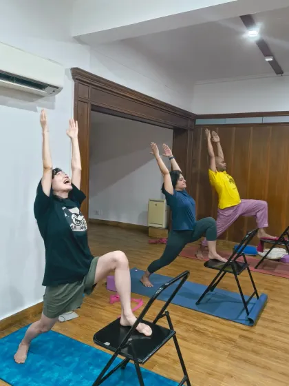 A new week brings new possibilities. Students using chairs to find lift and openness in a supported warrior pose, showing how props can make challenging poses more joyful.