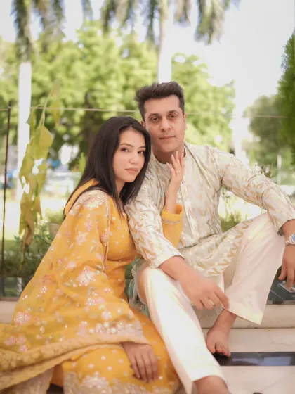 A stylish pre-wedding photo of the couple seated together. Their relaxed poses and direct gazes create a modern and confident portrait.