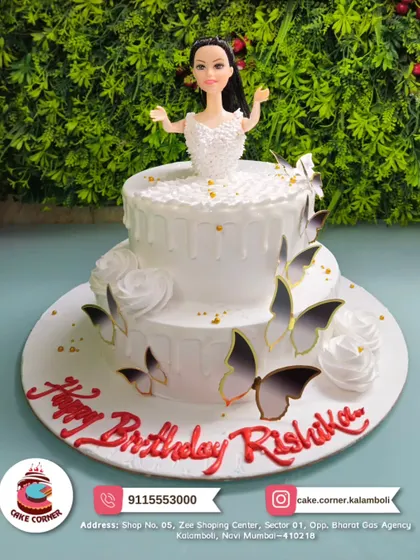 An elegant two-tier doll cake in white, decorated with delicate butterflies and white roses. A simple yet beautiful design for Rishika's birthday.