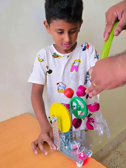 We explore engineering principles with fun, practical experiments. This student is testing a water turbine they assembled, discovering the power of hydro energy by turning a simple flow of water into mechanical motion.
