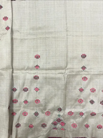 This off-white checked saree is embellished with small, colorful Kasuti butis, growing denser towards the pallu. It's a playful yet traditional design.