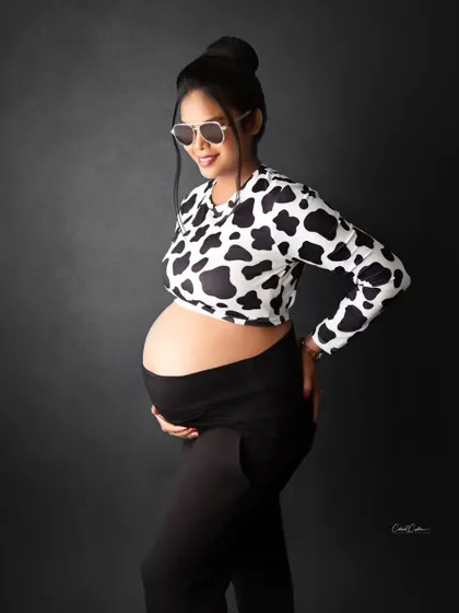 A cool and casual studio shot. The mom-to-be rocks sunglasses and a patterned top for a modern and stylish maternity look.
