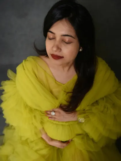 A serene, high-fashion portrait. The mom-to-be's closed eyes and gentle touch on her bump convey a moment of peaceful connection.