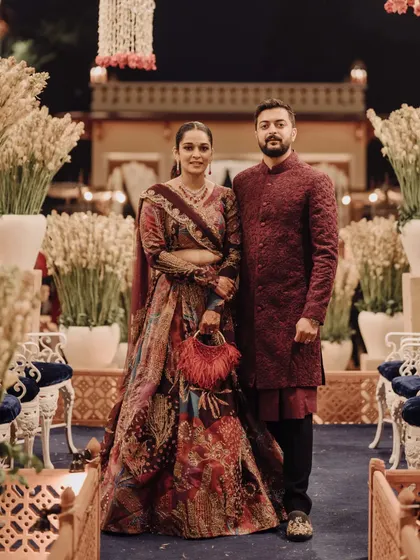 A full-length shot of a couple I styled, featured by WeddingSutra. Their coordinated outfits in shades of burgundy and maroon showcase a deep, royal color palette.