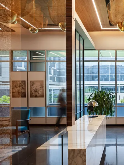 The reception area at the APT office, where a marble desk and warm lighting create an upscale first impression. The blurred motion of a person adds a dynamic quality, suggesting a bustling yet organized environment.