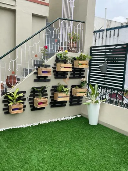 A creative use of space under a staircase on a terrace, where we installed a vertical planter system using wooden crates for a rustic, charming look.