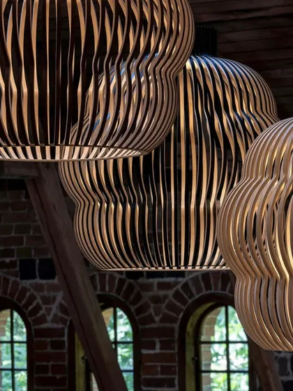 A close-up, low-angle shot of several Kuulto pendants, emphasizing the rhythmic pattern of the wooden slats and the warm light emanating from within.