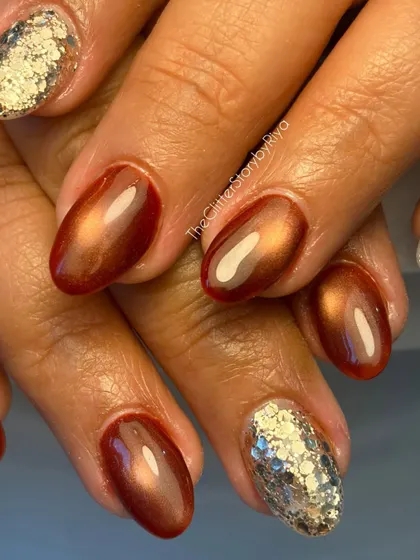 A close-up of a warm, coppery cat-eye manicure. This set is paired with a chunky silver glitter accent nail for a beautiful contrast of textures.