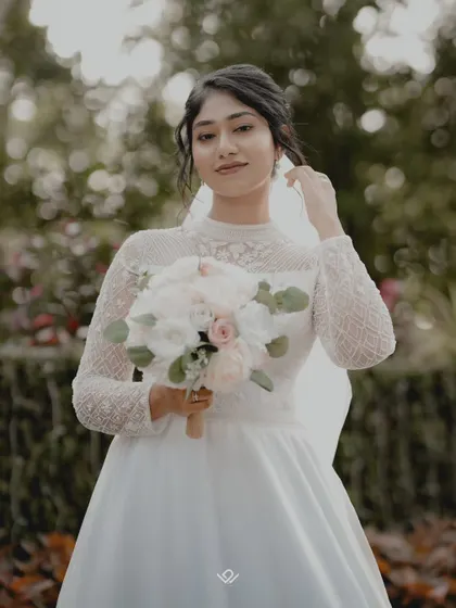 A classic bridal portrait in a garden setting, with the bride looking confidently at the camera.