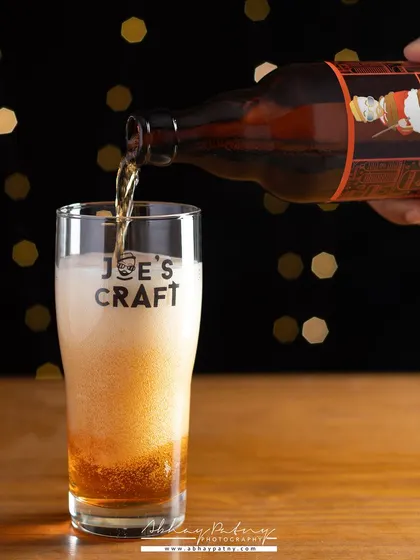 The action of pouring beer into a glass, with a festive bokeh background, creates a celebratory mood. This shot is perfect for promoting a beer brand during holidays or events.