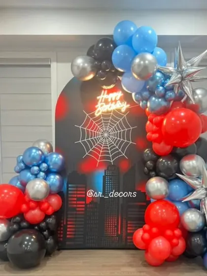 Your friendly neighborhood 'Spider-Man' swings into the party with this themed backdrop, featuring a city skyline, a spider web graphic, and a red, blue, and black balloon garland.