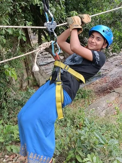 A smiling participant confidently traverses a rope line during our adventure camp.
