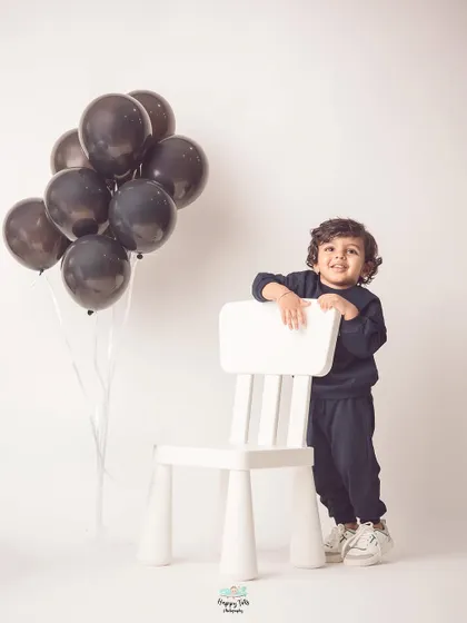 A stylish portrait with a simple chair and balloons. This minimalist setup keeps the focus on his adorable personality.