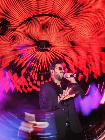 A creative, artistic shot of a live singer on stage, captured with a slow shutter speed to create a dynamic swirl of light.