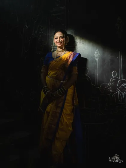 An artistic portrait of a bride in a traditional Nauvari saree, using dramatic light and shadow to create a powerful image.