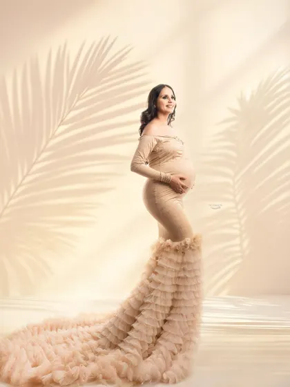 This portrait showcases a gorgeous beige gown with a dramatic ruffled train. The soft lighting and subtle palm leaf shadows create a warm, almost tropical feel in this studio setup.