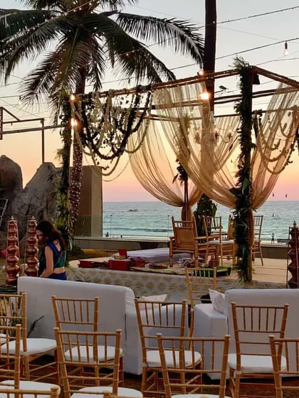This rustic mandap design uses natural elements like wooden poles and decorative beaded hangings. The setup is enhanced by comfortable white sofas for family seating, creating a relaxed and intimate vibe.