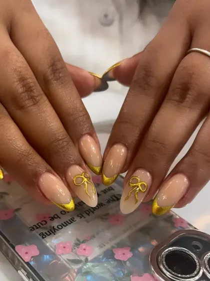 A cute and classy French manicure with a twist. This design features gold chrome tips and a delicate 3D gold bow accent.